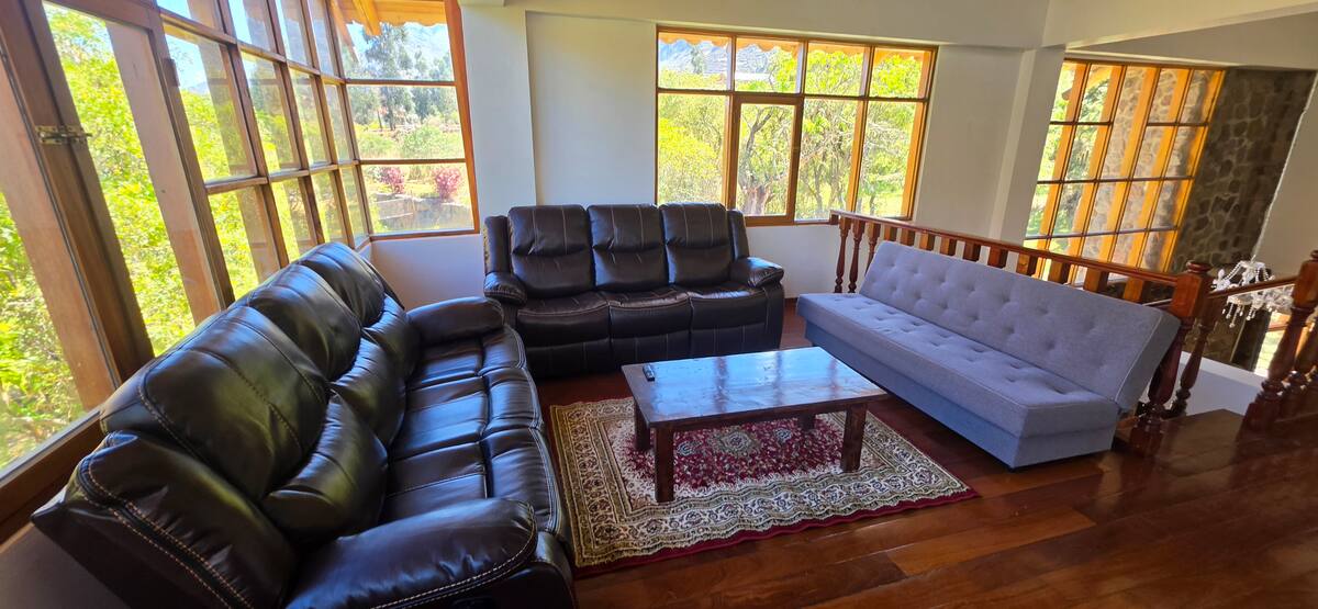 Segunda sala de estar con sofás y ventanal hacia el jardín