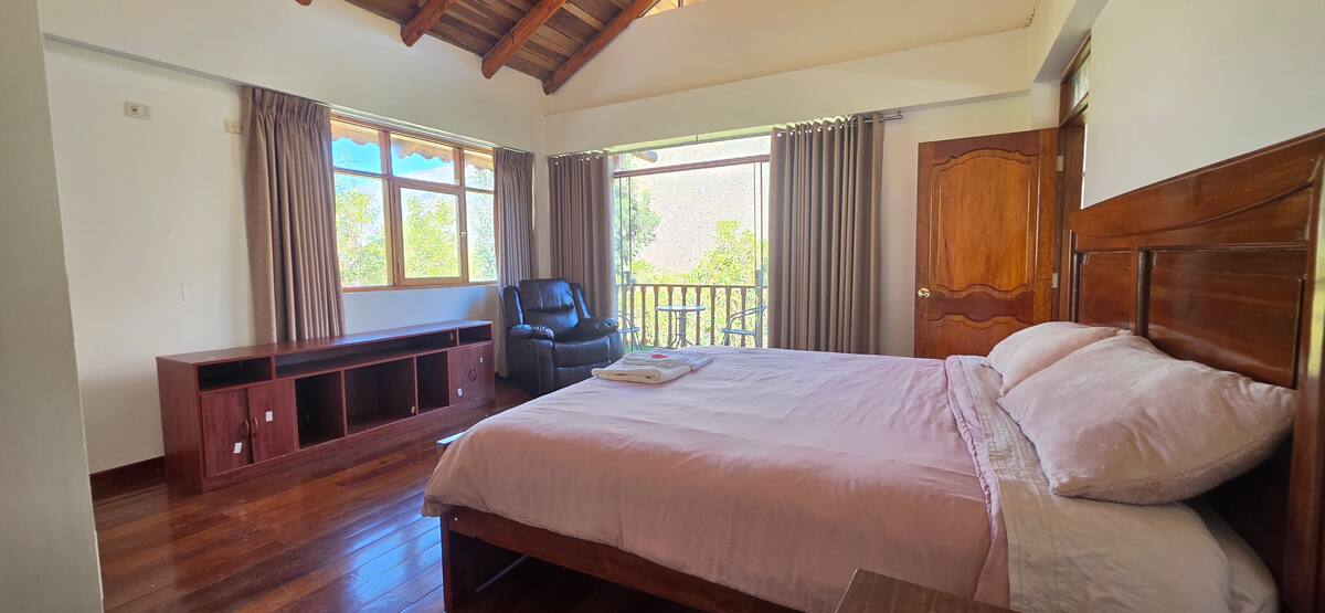 Habitación principal con cama king, sofá y ventanales con vista