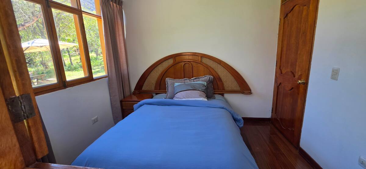 Habitación con cama doble y ventana con vista al valle