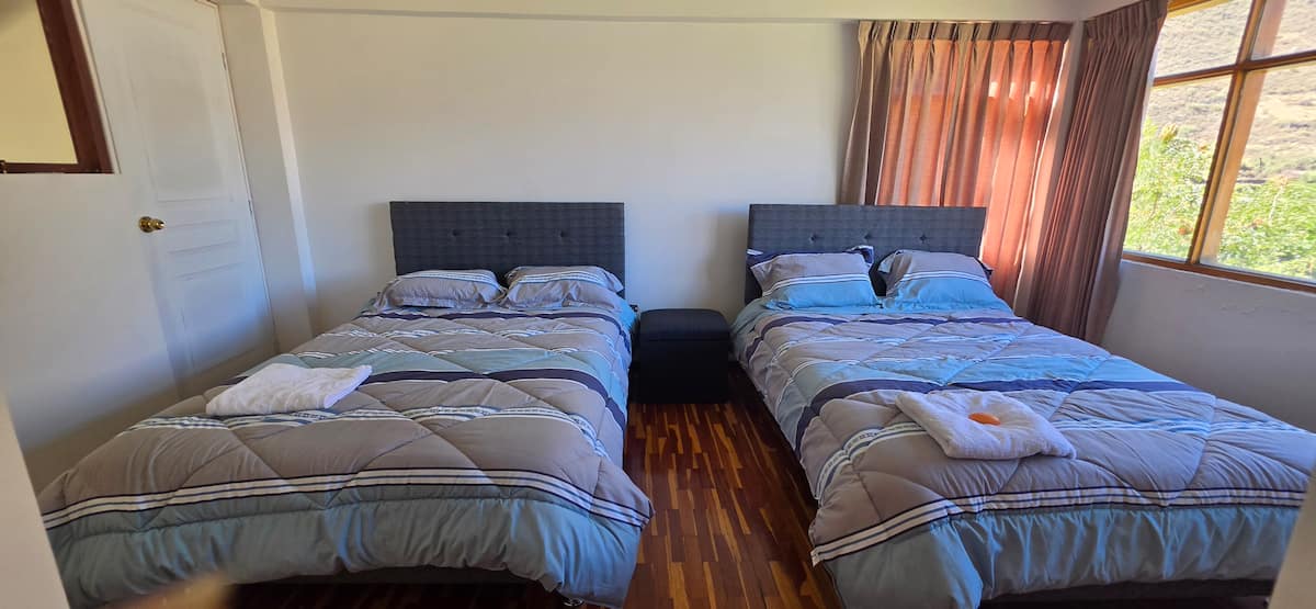 Habitación con dos camas y ventanal con vista al jardín
