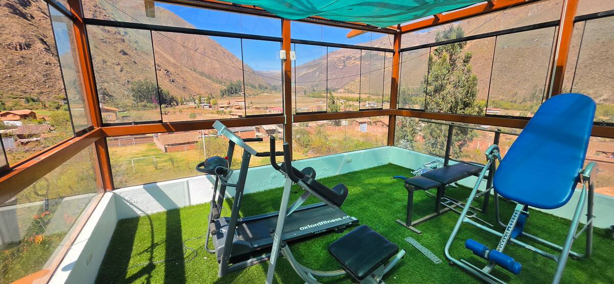 Equipos de ejercicio frente a grandes ventanales con vista al valle