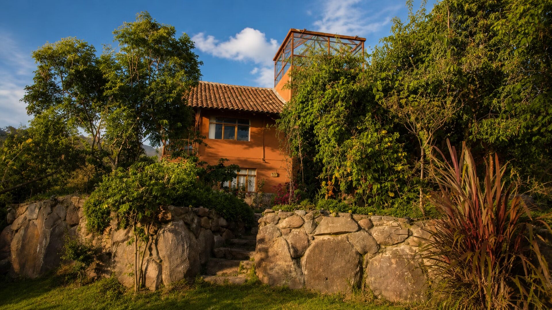 Vista lateral de la casa con techos de teja y muros de piedra