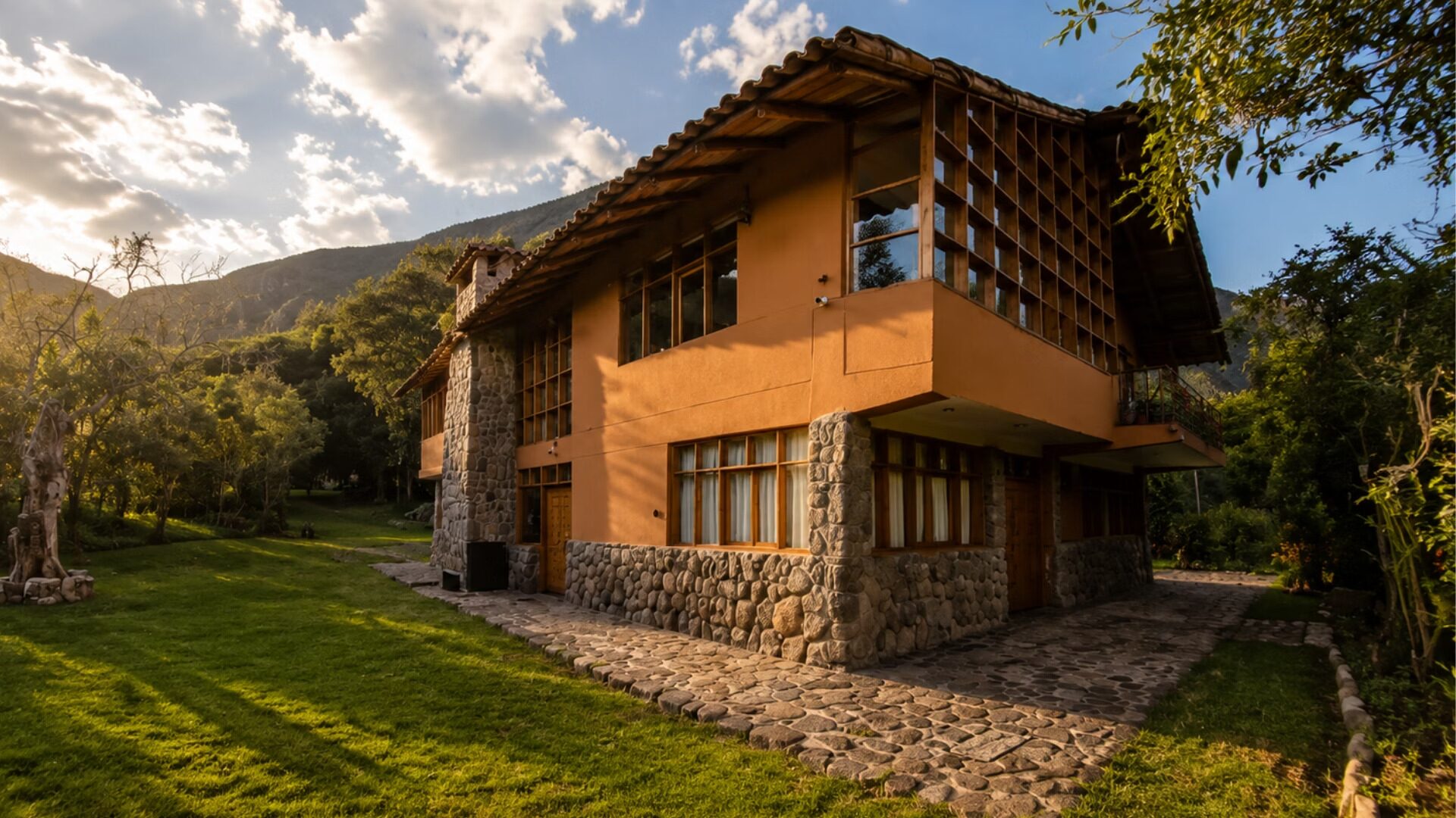 Exterior con muros de piedra rodada y muros de adobe en tonos terracota