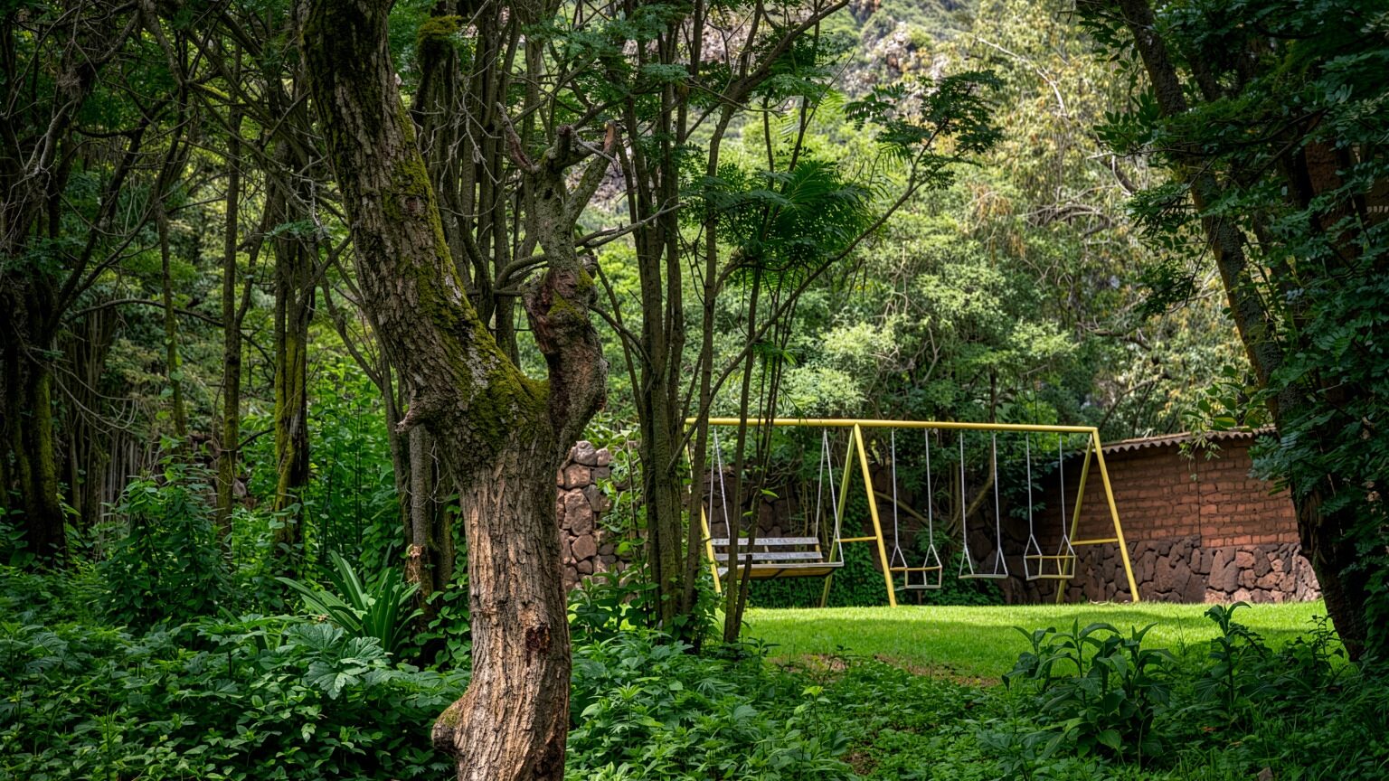 Zona de juegos con columpios entre árboles del jardín